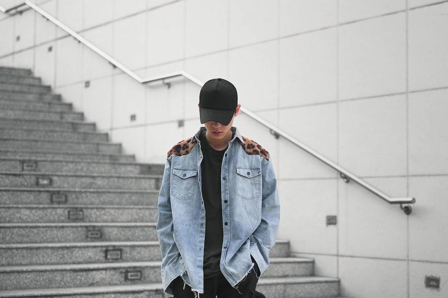 man wearing a denim jacket and black truck hat