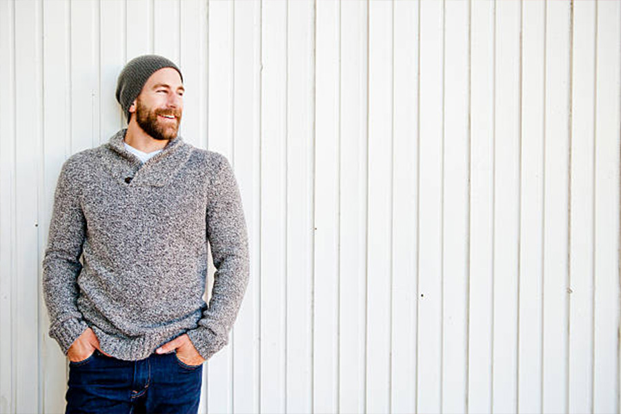 Man wearing a gray sweater with a green skull beanie