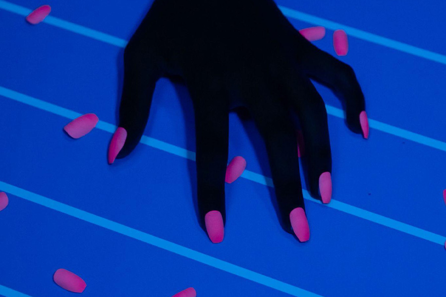 Pink press-on nails under a blacklight.