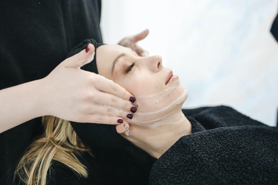 Relaxing woman applying cream in a spa