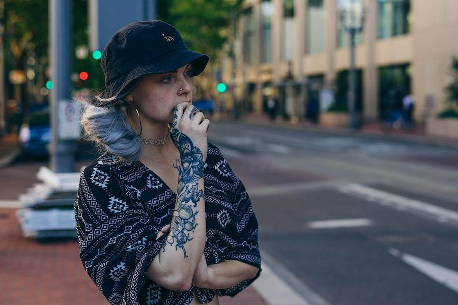 Tattooed woman rocking a dark-toned bucket hat