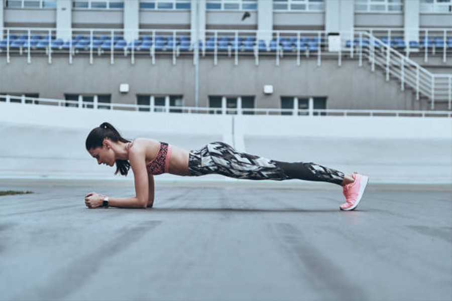 Woman doing the plank wearing patterned leggings and bra