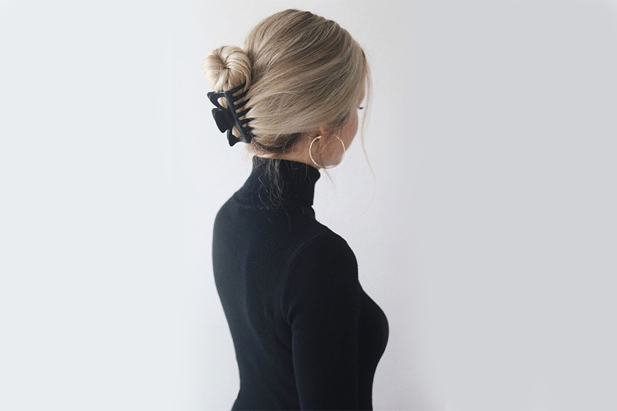 woman securing a bun with medium hair claw clip