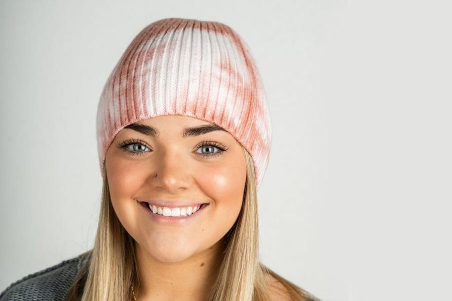 Woman smiling in a tie-dye beanie