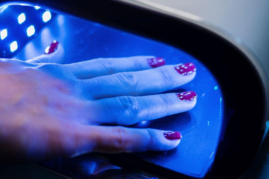 Woman under the gel manicure lamp.