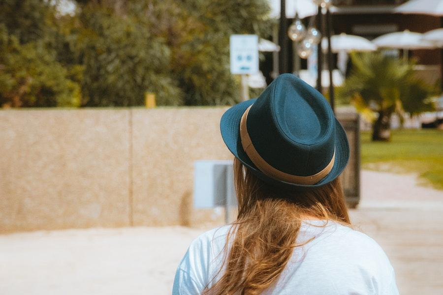 Woman wearing a black fedora with a gold stripe