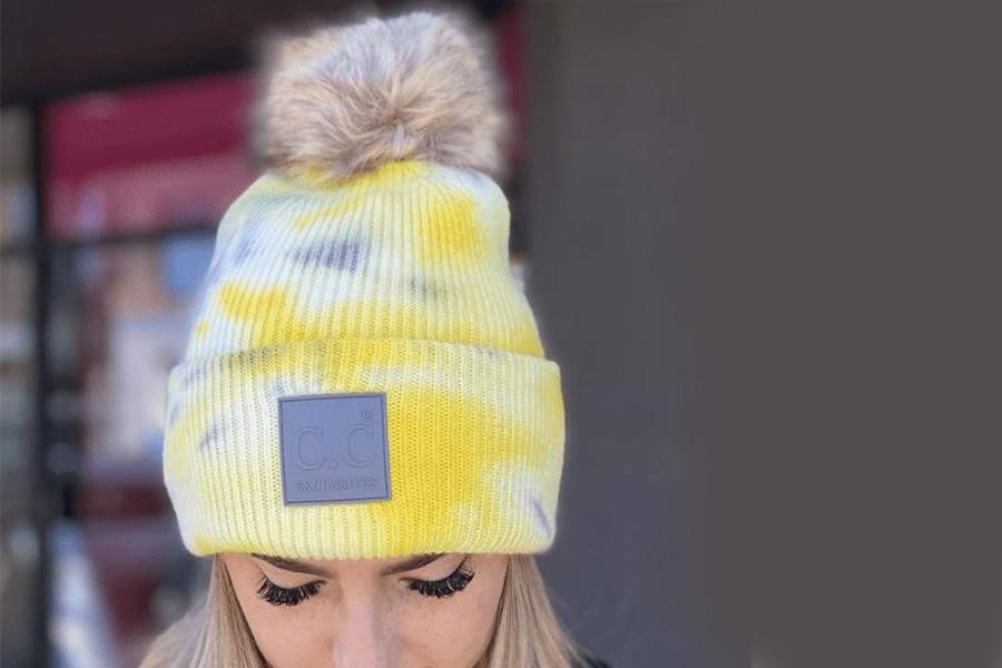 Woman wearing a yellow tie-dye pompom beanie