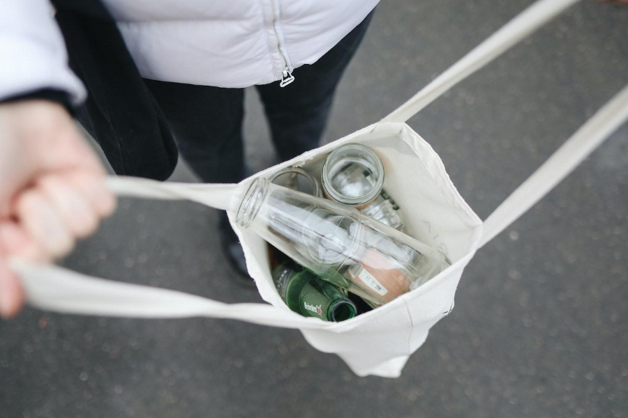 A lady holding a bag with empty bottles