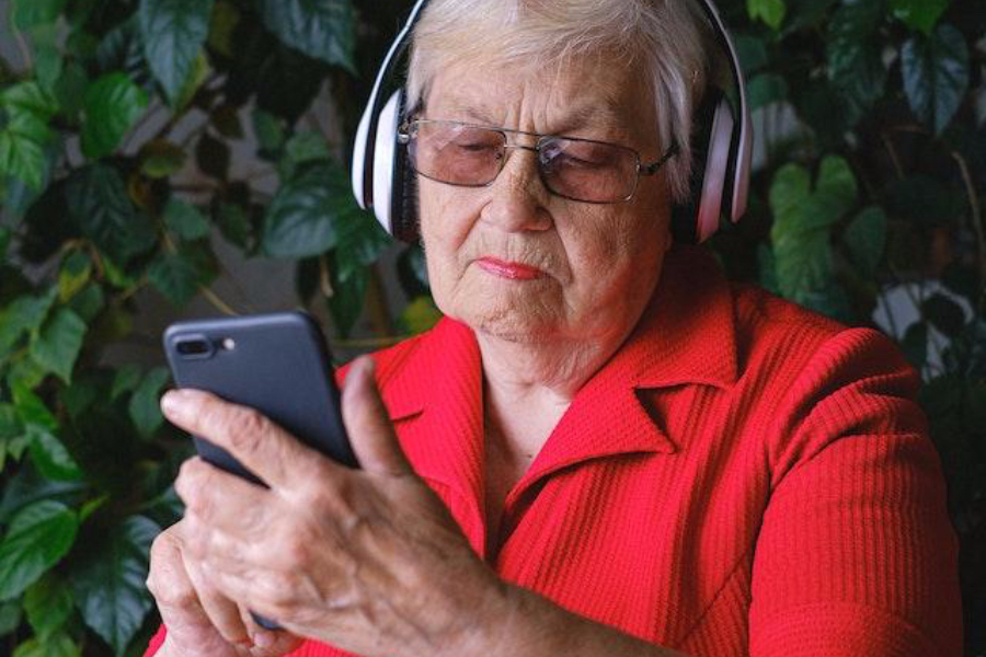 A senior woman in headphones using smartphone