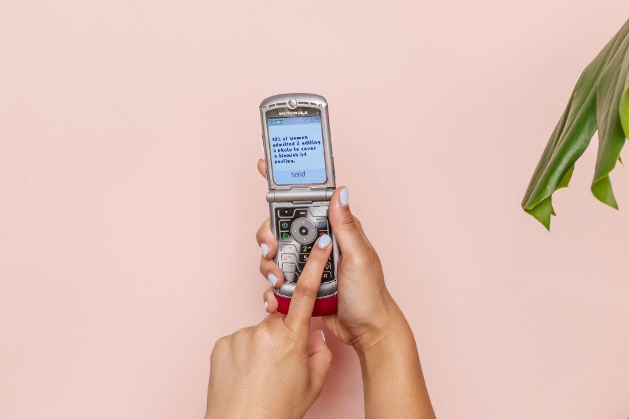 A woman operating a silver color flip phone