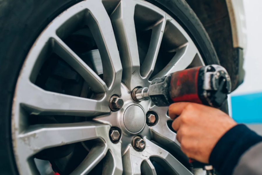 Anonymous hand using an impact wrench to lose a tire