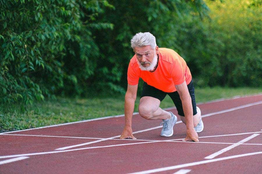 Man in running position wearing orange shirt and shorts