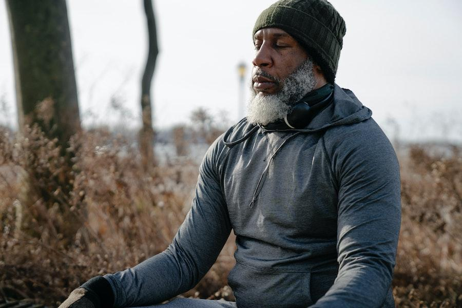 Man meditating in a gray hoodie and beanie