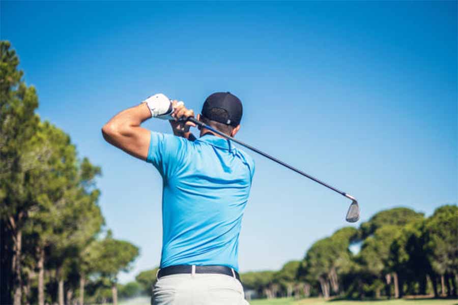 Man teeing off at a golf course on a sunny day