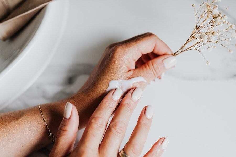 Woman holding a small branch while applying hand cream