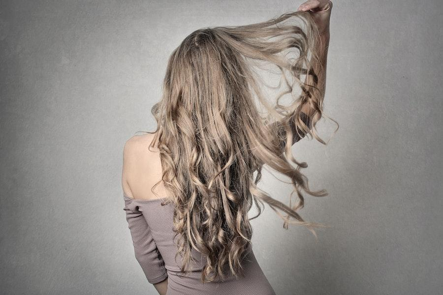 Woman holding her hair wearing a gray off-shoulder dress