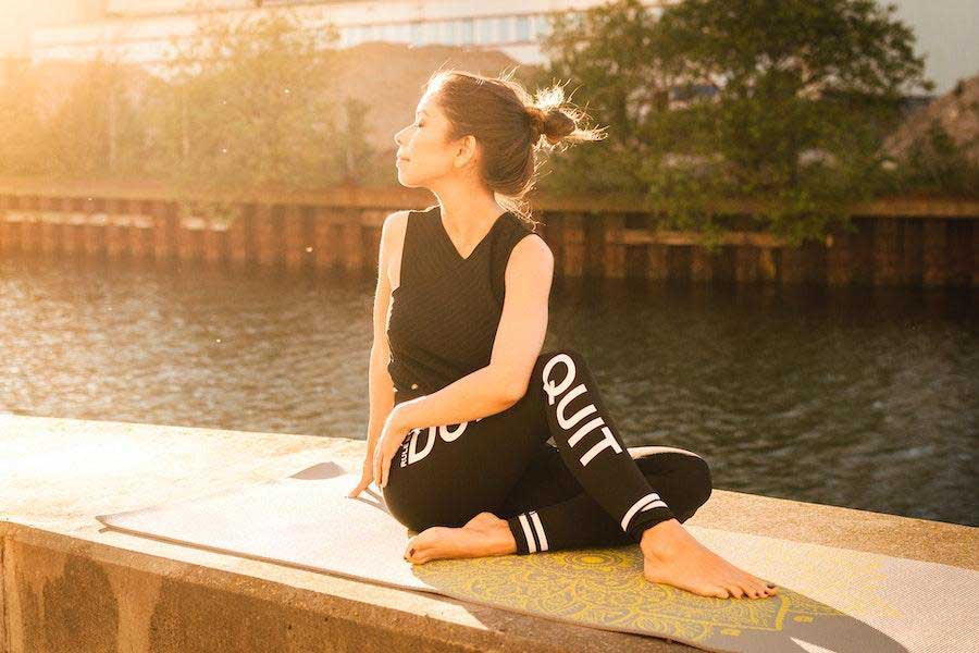 Woman in all-black outfit while sitting on a yoga mat