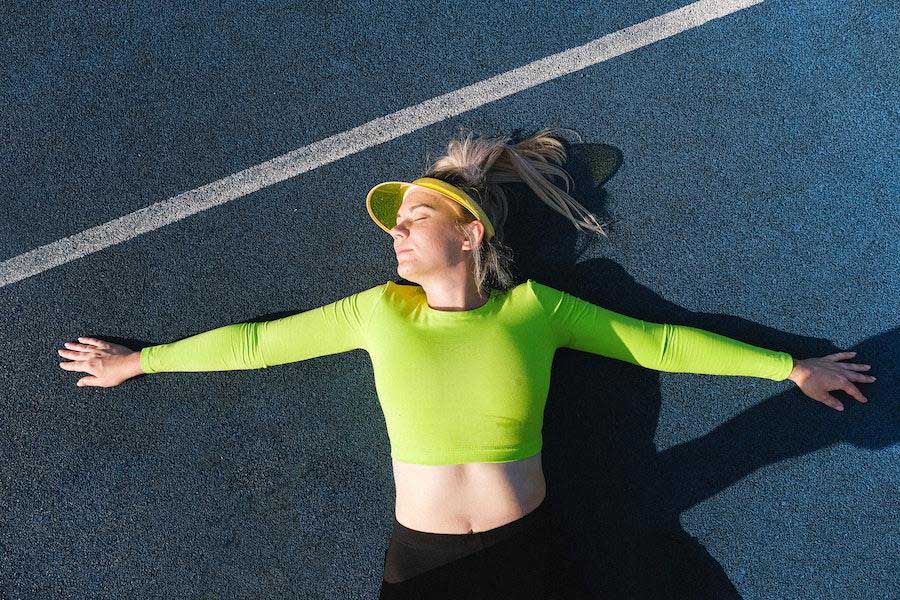 Woman lying on a field in a green cropped tank