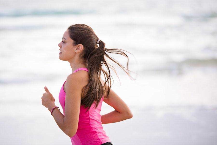 Woman running while wearing a pink tank top