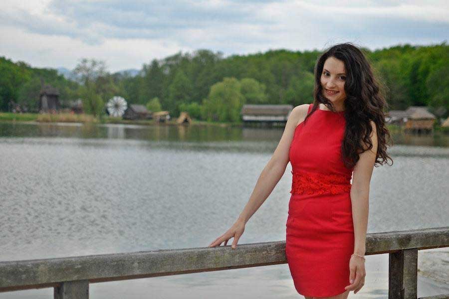 Woman standing near railings in a fitted red dress