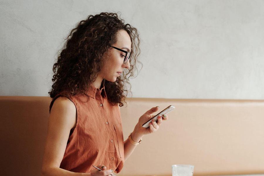 Woman with curly brown hair looking at her phone