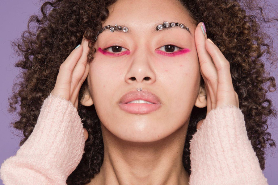 Woman with jewels on her eyebrows and pink eye makeup