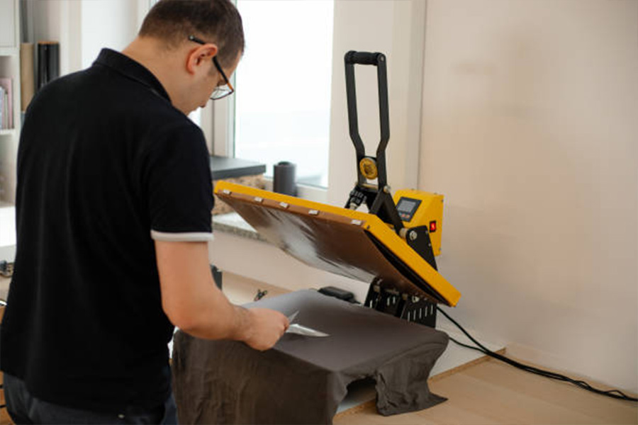 A man using a heat thermal textile application transfer press