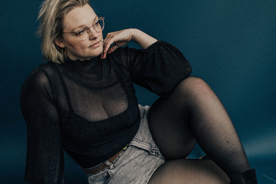 Lady wearing a black see-through blouse and denim shorts