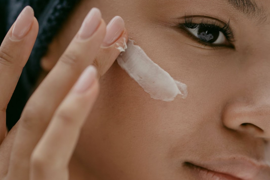 Woman with blush nails applying skincare products