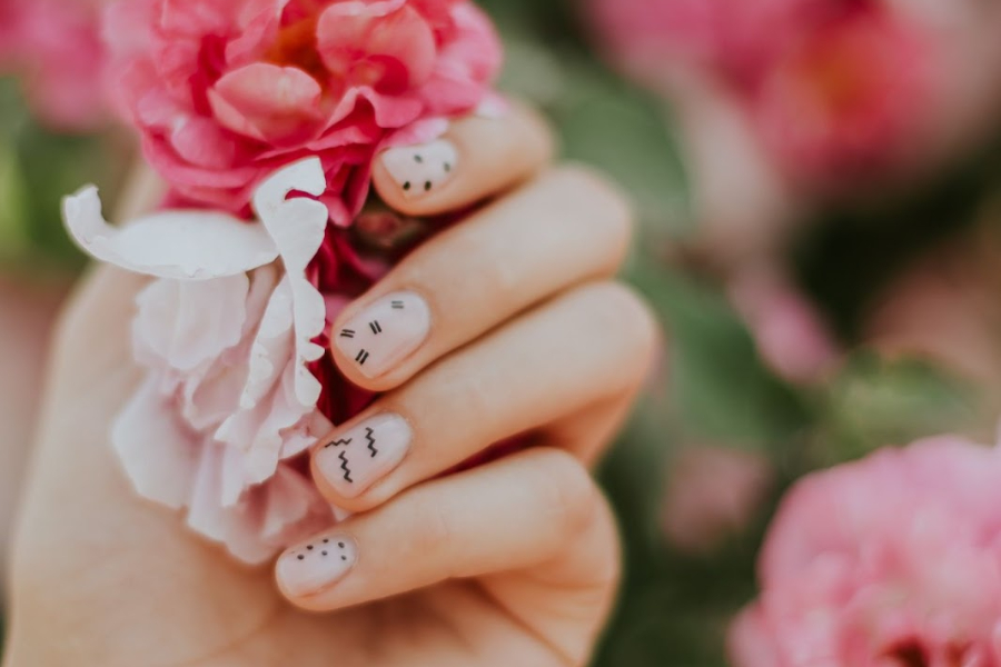 Woman’s hand with neutral nail polish and various stickers